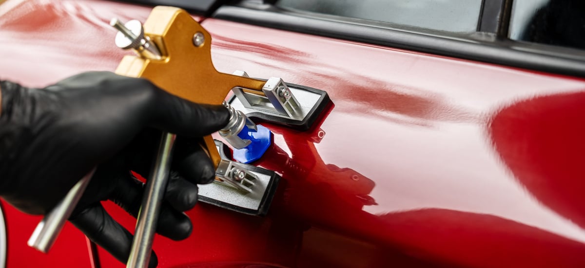 Paintless car dent repair technician fixing a damaged vehicle door with PDR technology